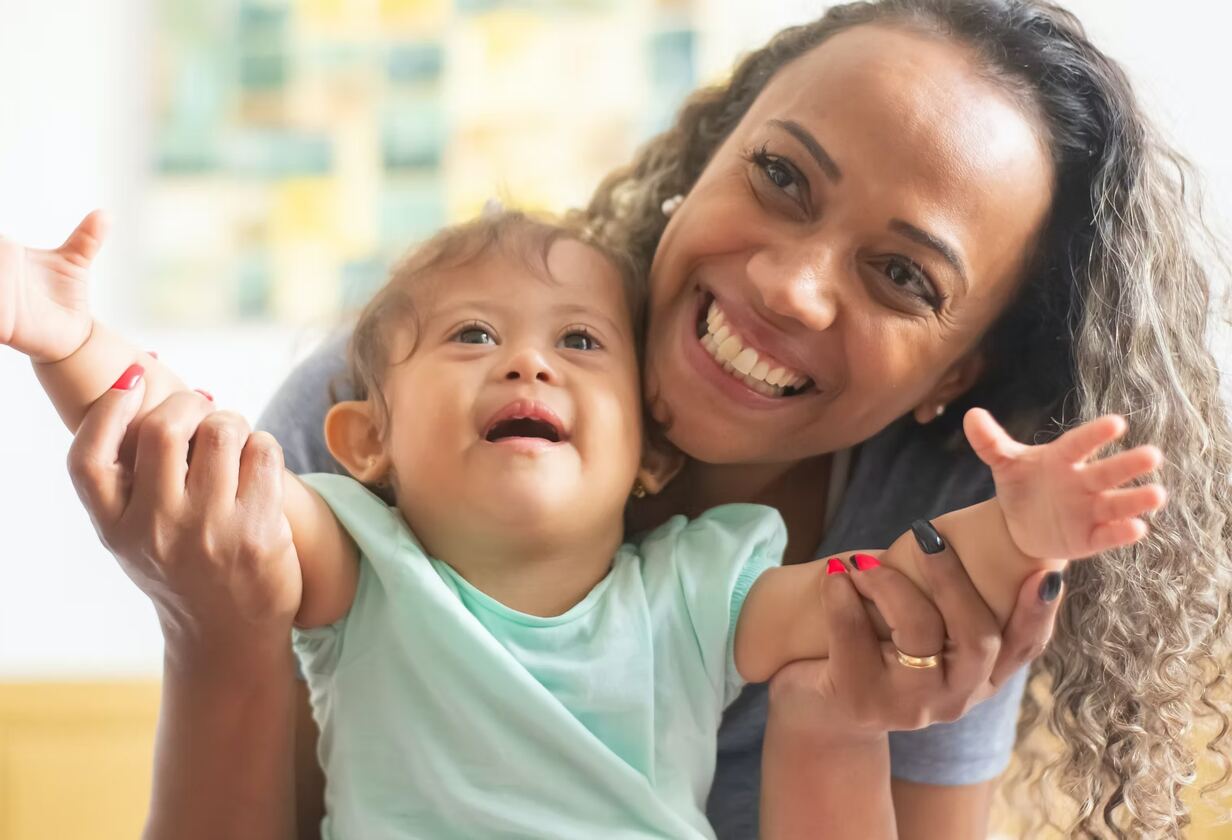 A respite worker  holding a smiling young child at home